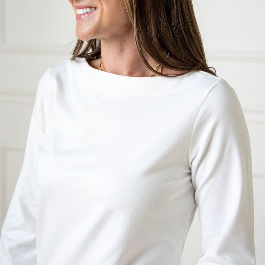 Woman wearing a white long-sleeve shirt against a plain background