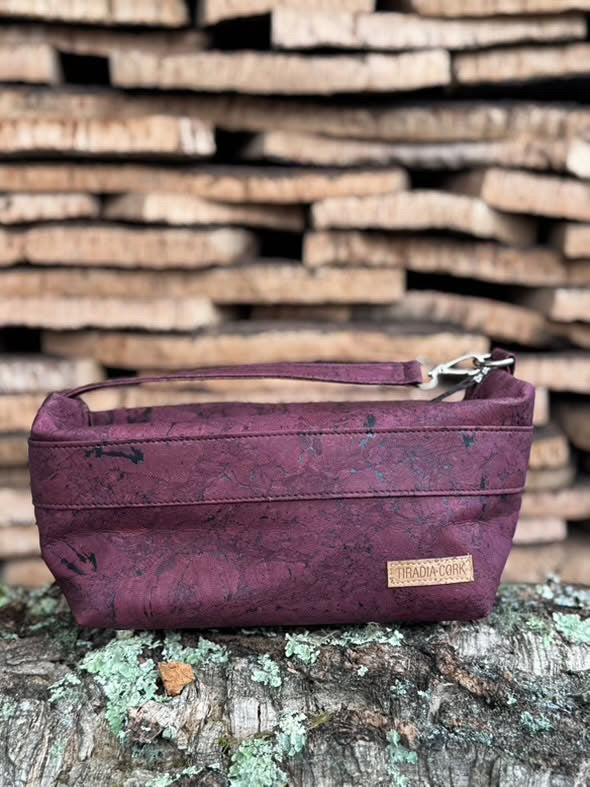 Purple cork handbag on a wooden surface with a stack of wooden planks in the background