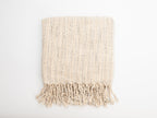 Beige woven blanket with fringes on a white background