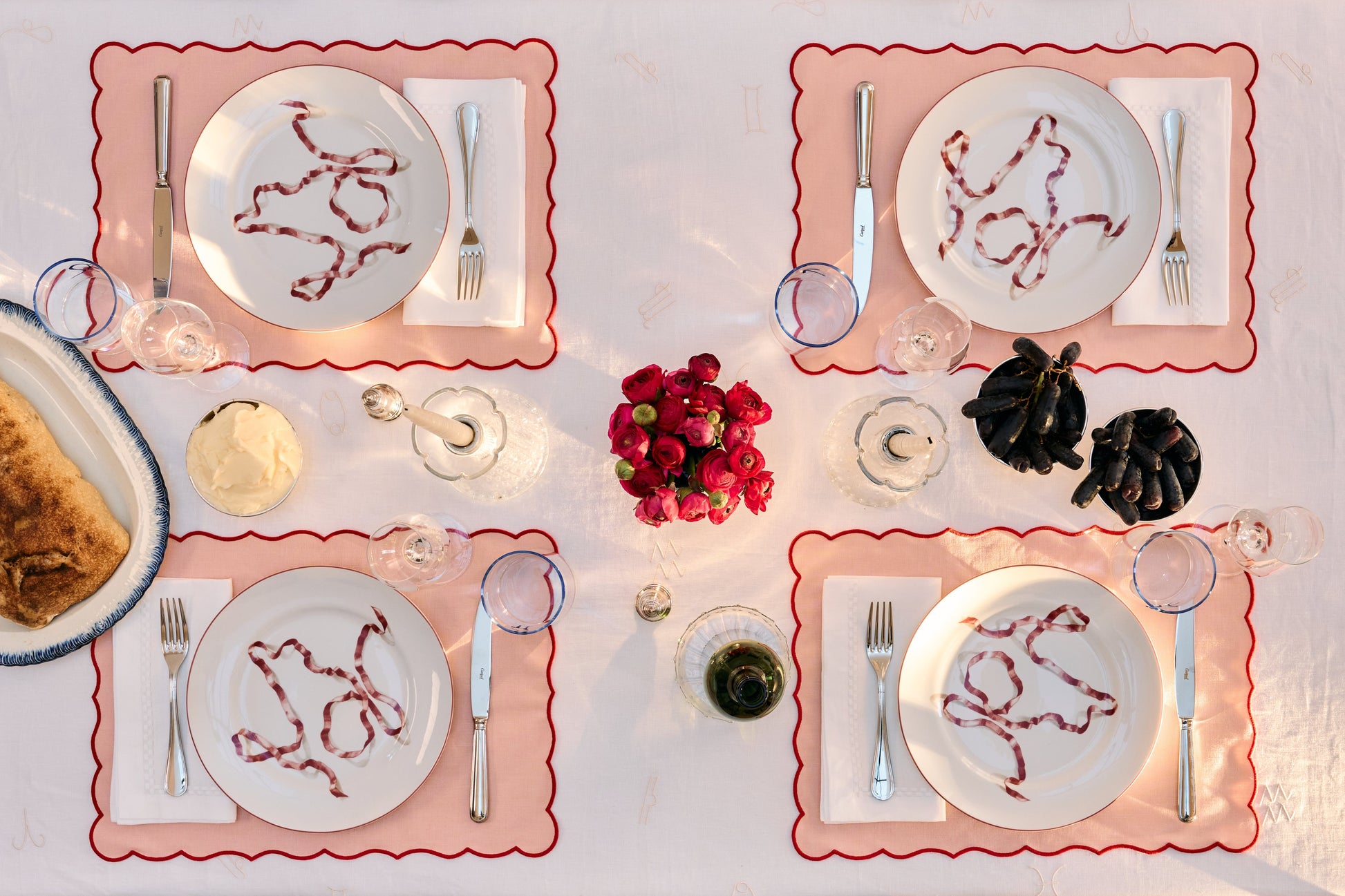 Dining table set with plates, cutlery, and decorative items on a white tablecloth.