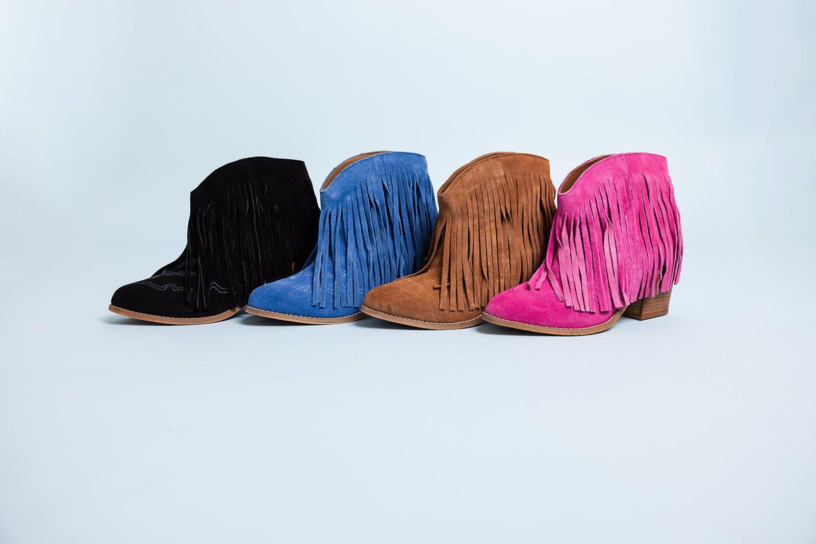 Four pairs of colorful fringe boots on a light gray background