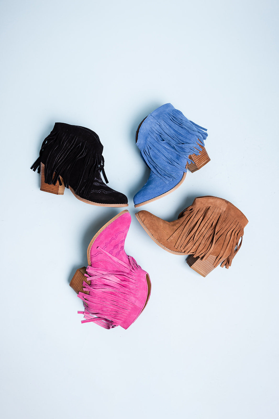 Four colorful fringe boots on a light blue background