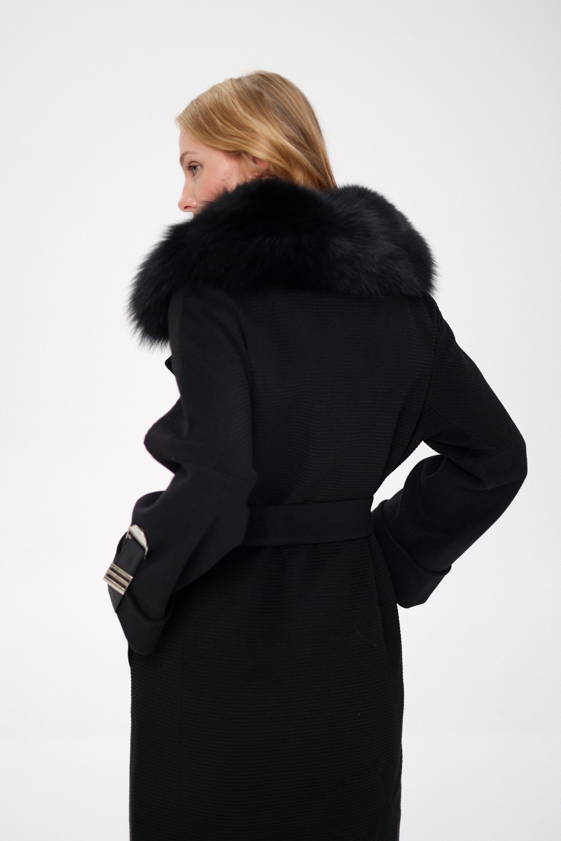 Woman wearing a black coat with a fur-lined hood on a white background
