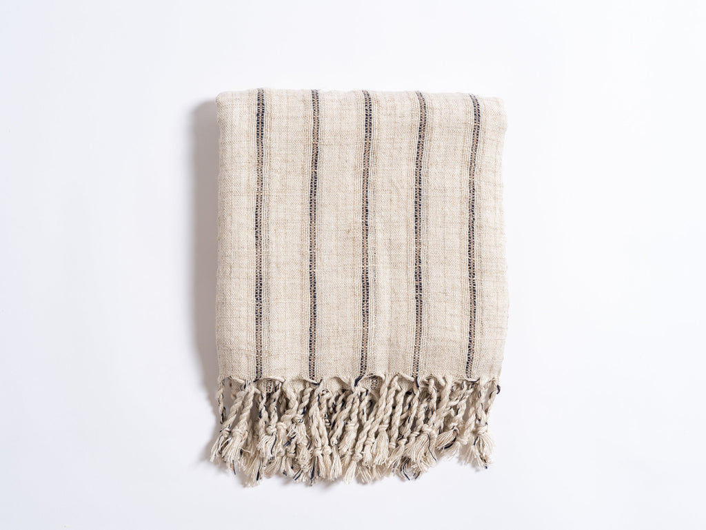 Textured towel with black stripes and frayed edges on a white background