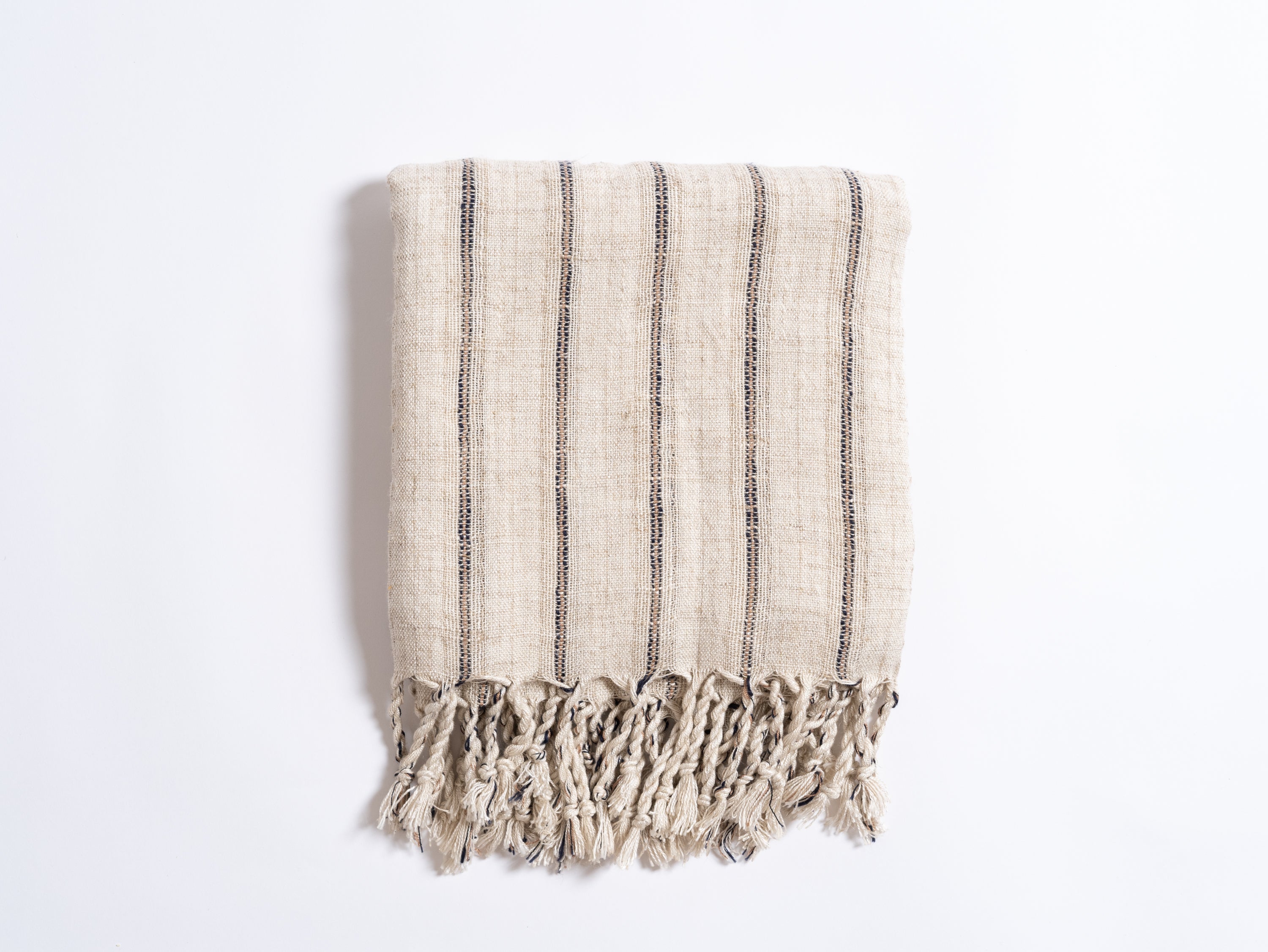 Textured towel with black stripes and frayed edges on a white background