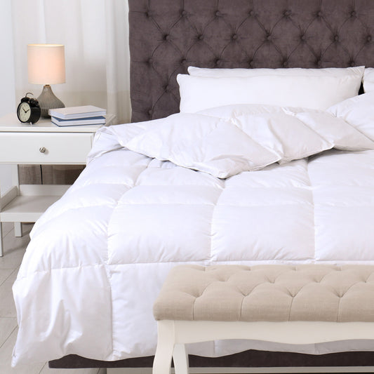White comforter on a bed with a tufted headboard and nightstand in a bedroom setting.