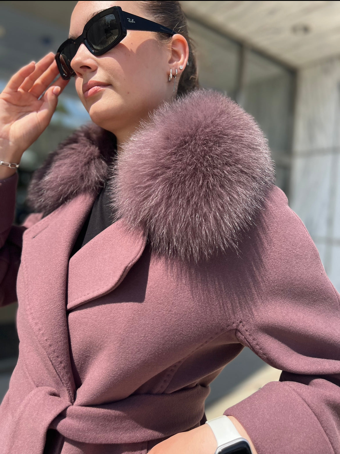 Person wearing a pink coat with a fur collar outdoors