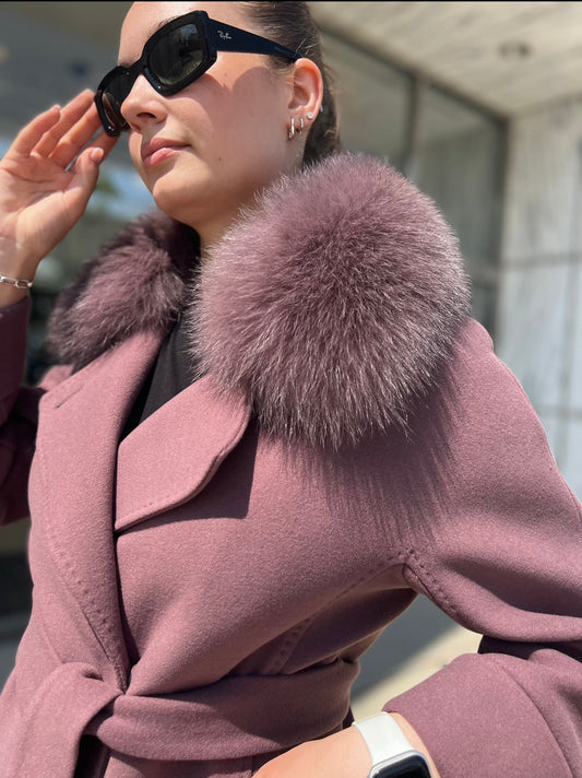 Person wearing a pink coat with a fur collar outdoors