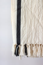 Textile with black and white fringes on a plain background