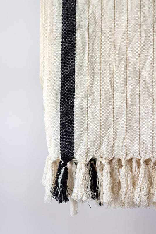 Textile with black and white fringes on a plain background