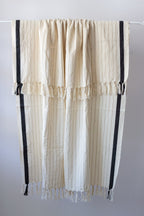 Striped curtain with black accents hanging on a rod against a white background