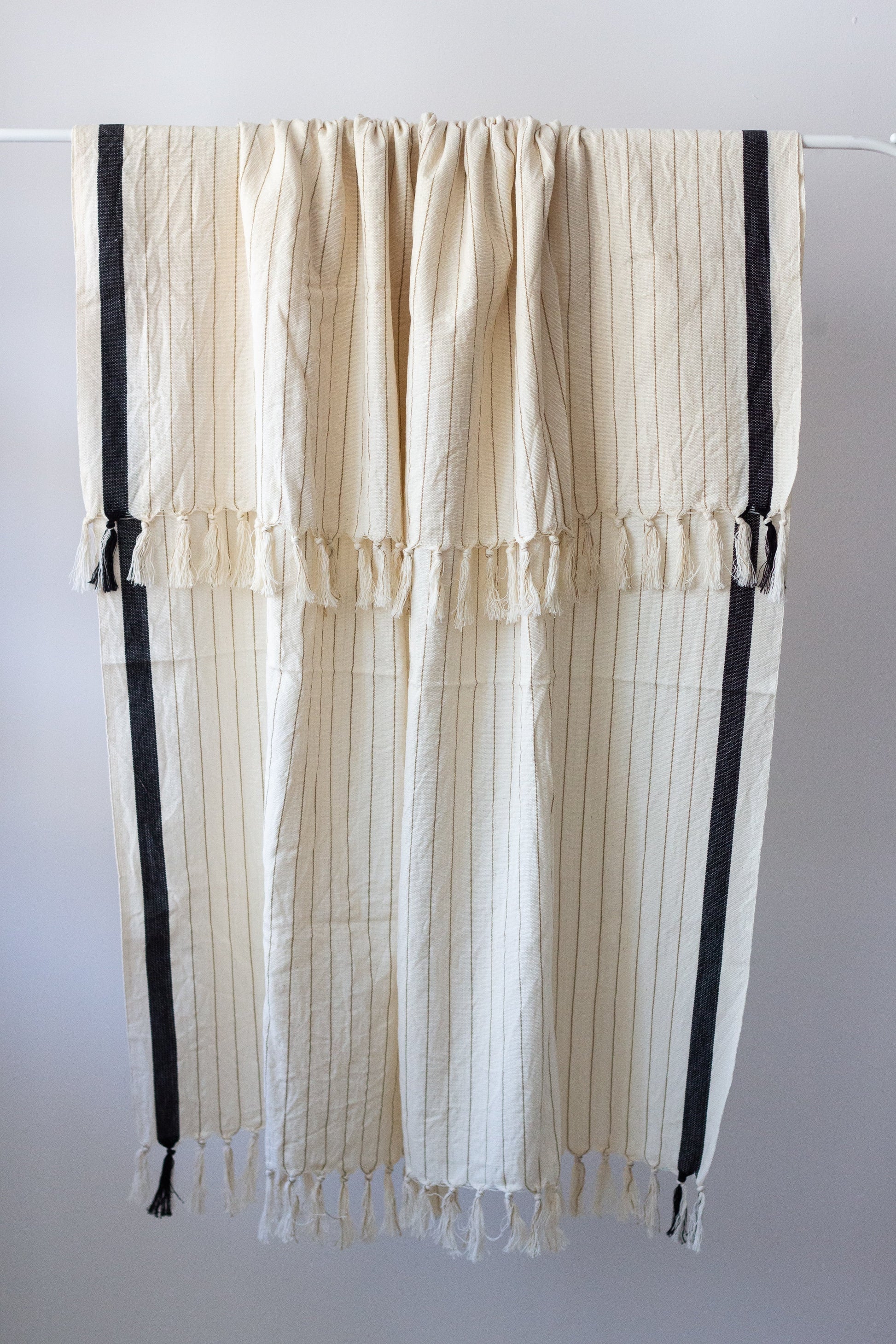 Striped curtain with black accents hanging on a rod against a white background