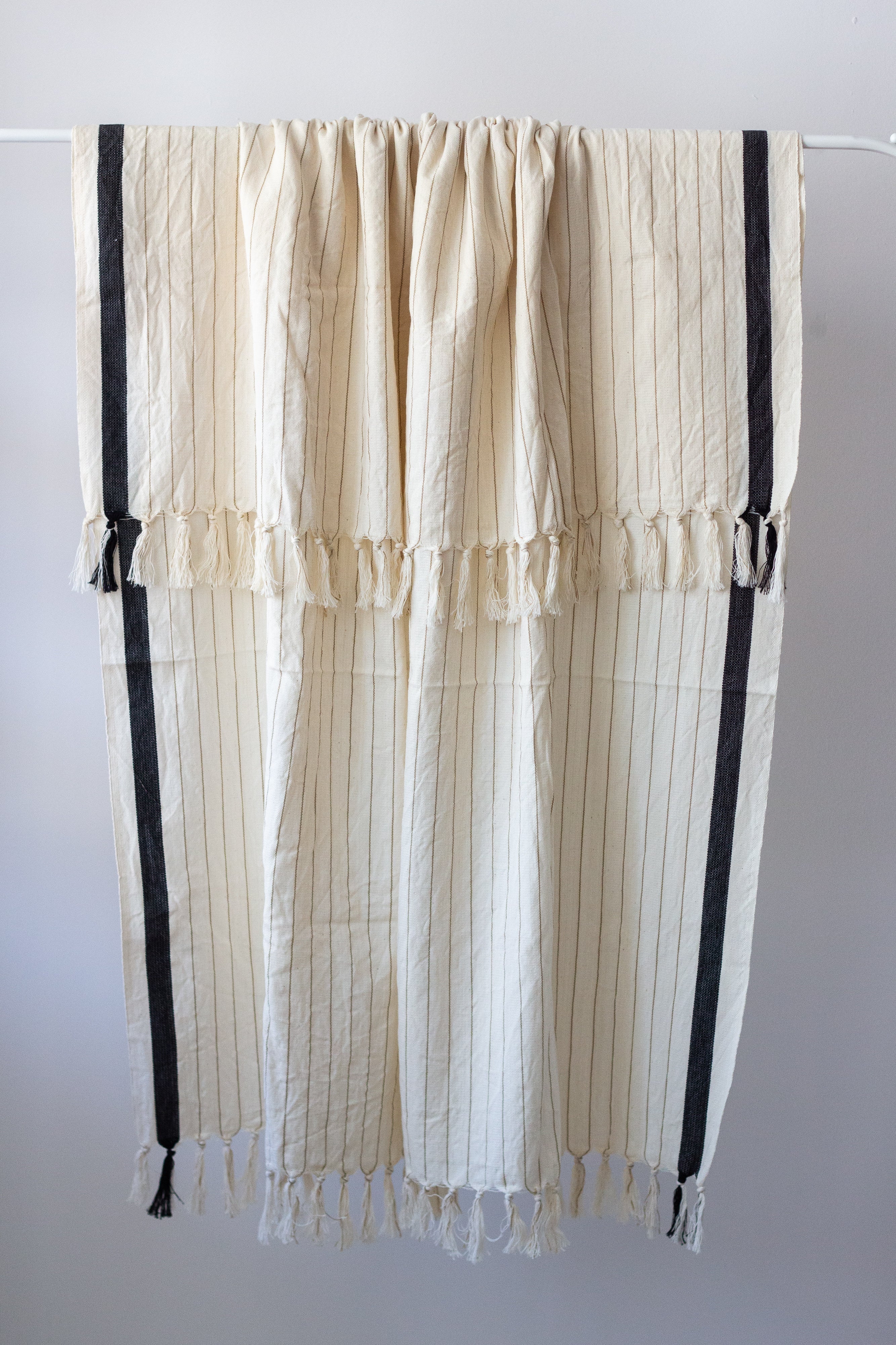 Striped curtain with black accents hanging on a rod against a white background