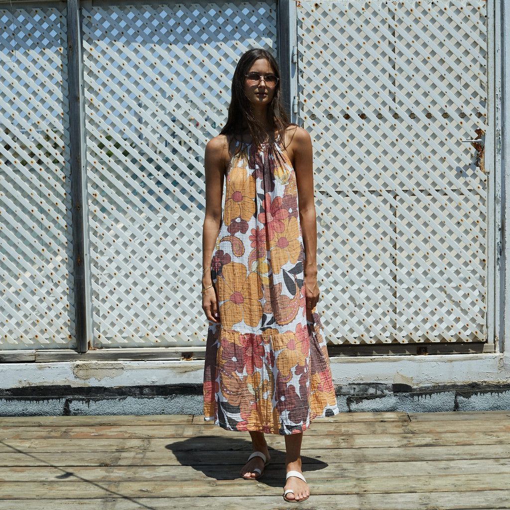 Woman wearing a floral dress standing on a wooden deck with a lattice background
