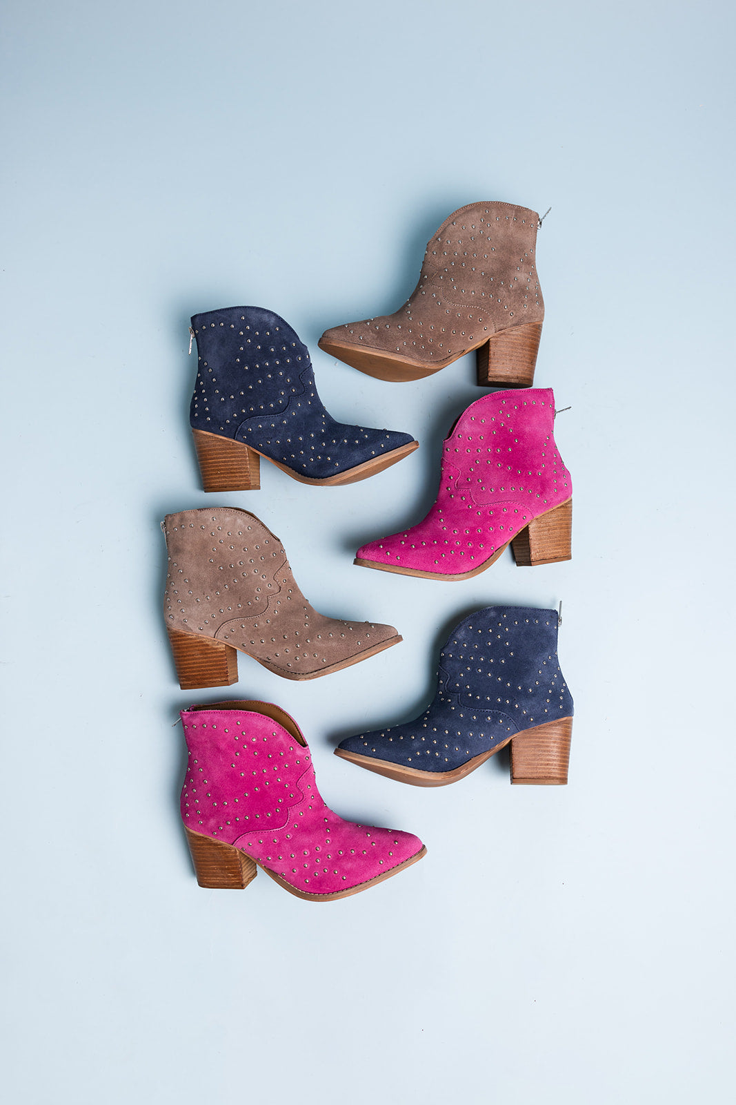 Set of colorful suede boots with wooden soles on a light blue background