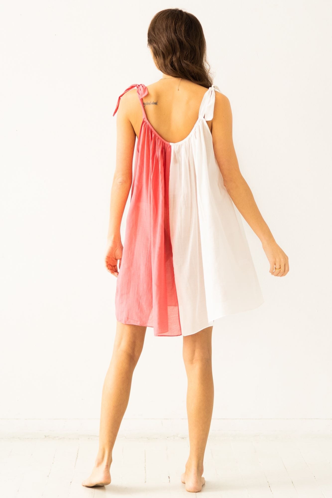 Woman wearing a two-tone dress with pink and white panels on a white background