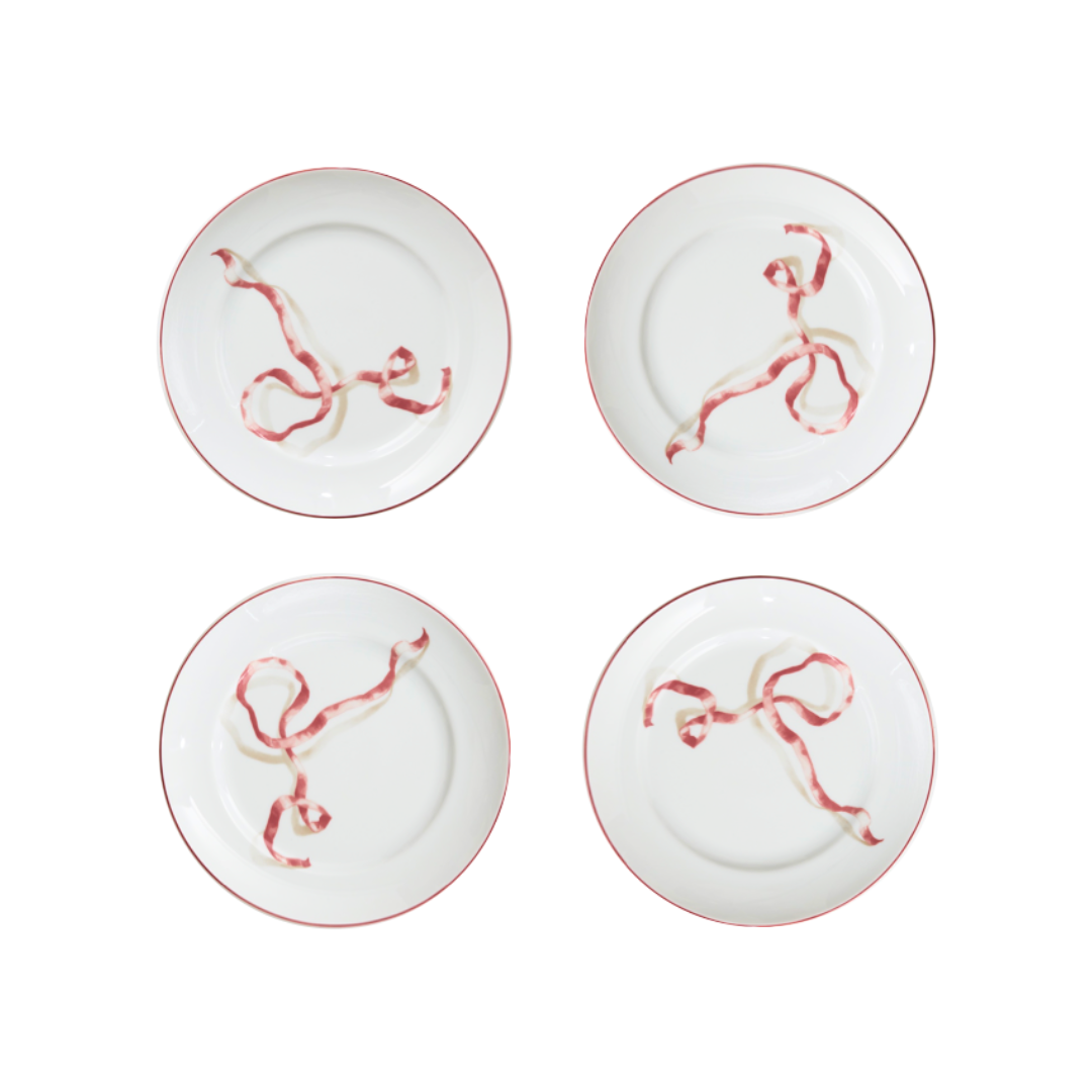 Four white plates with red abstract designs on a white background