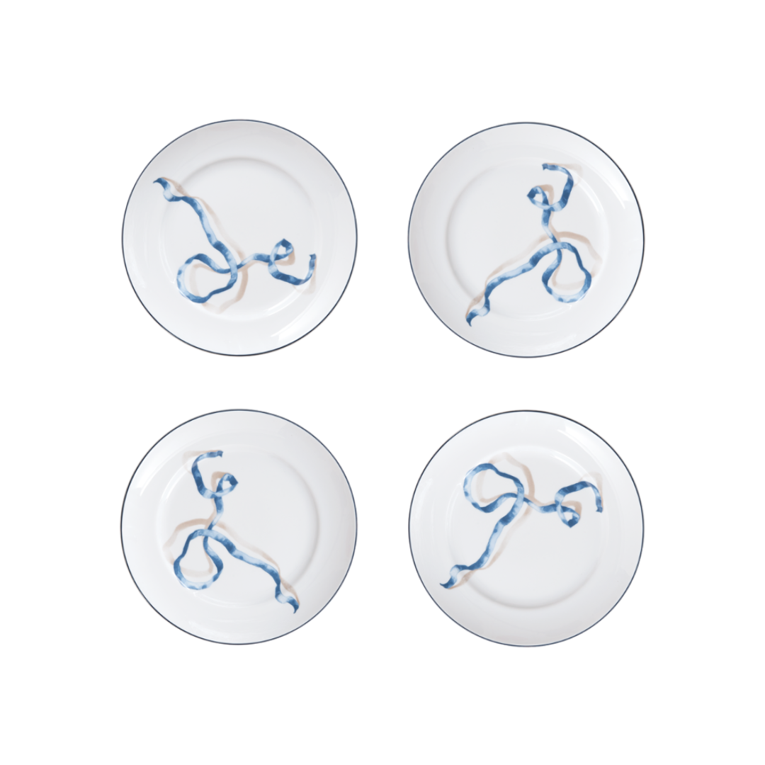 Four white plates with blue and gold abstract designs on a white background