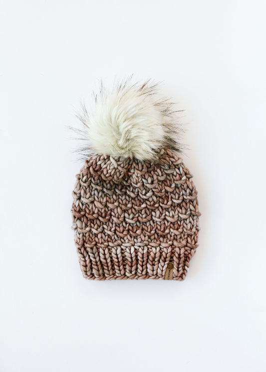 Knitted beanie with a fur pom-pom on a white background