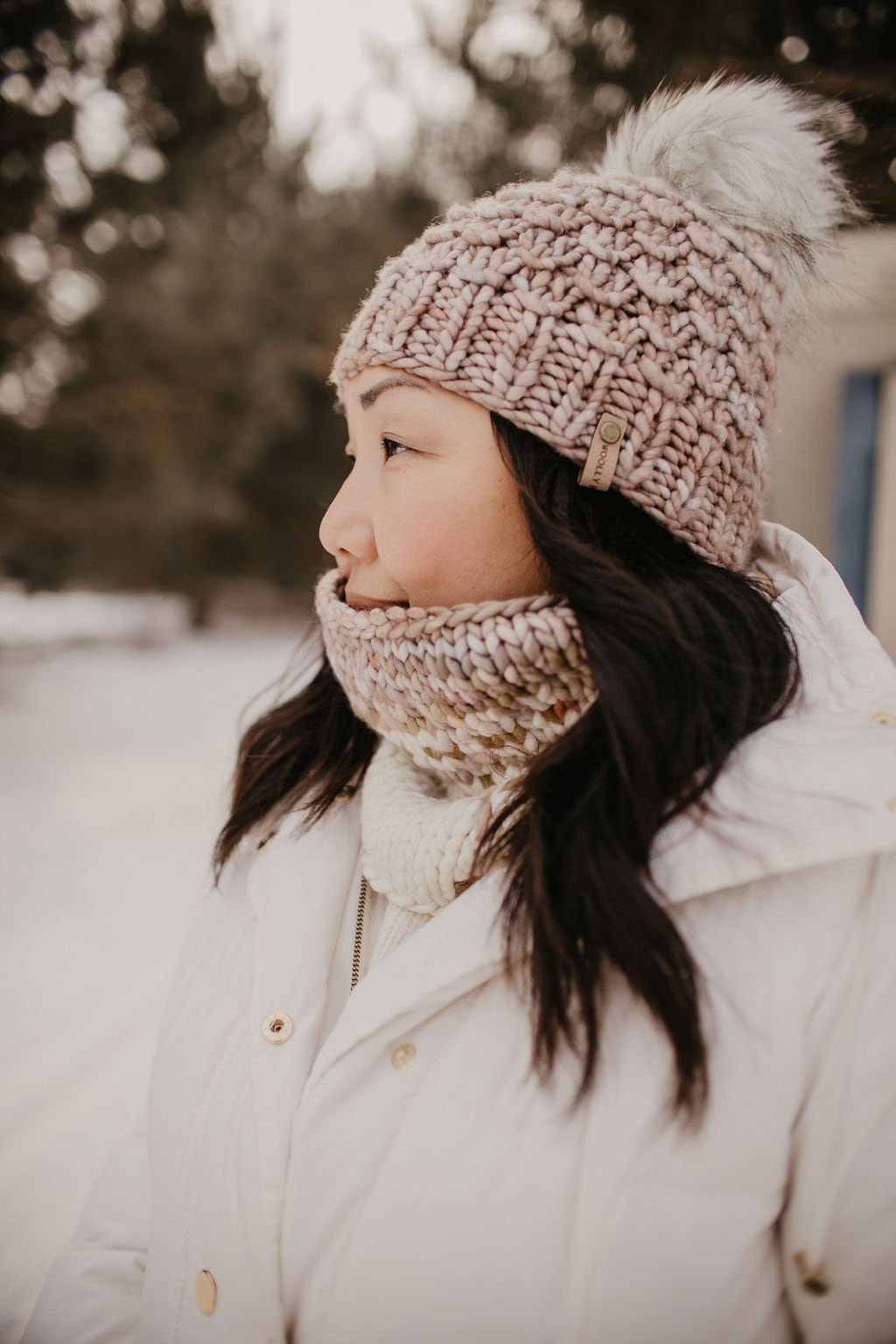 Woman wearing a knitted hat and scarf in a snowy outdoor setting