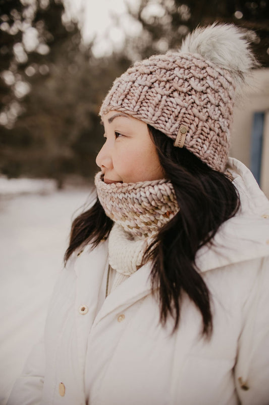 Woman wearing a knitted hat and scarf in a snowy outdoor setting