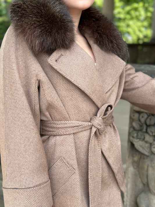 Beige coat with fur collar worn by a person, standing outdoors.
