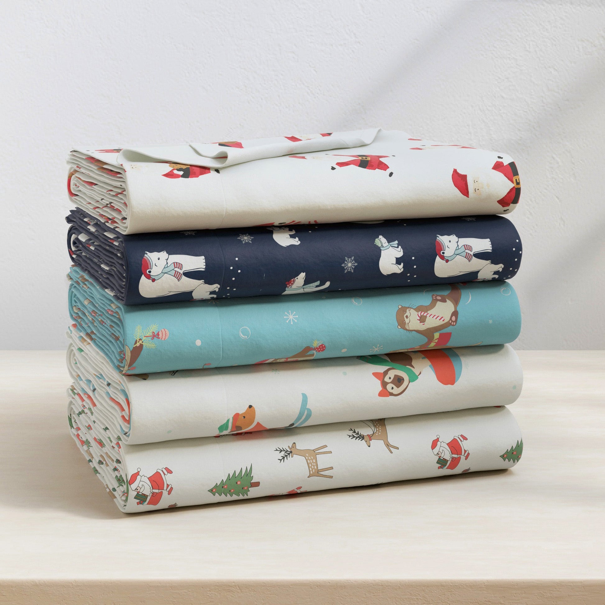 Stack of fabric sheets with Christmas-themed designs on a light surface.